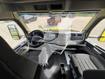 Peterbilt 579 cab interior showing dashboard, steering wheel, and driver seat with documents on floor.