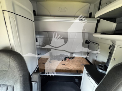 Peterbilt 579 sleeper cab interior showing cargo area with wooden floor platform and storage compartments.