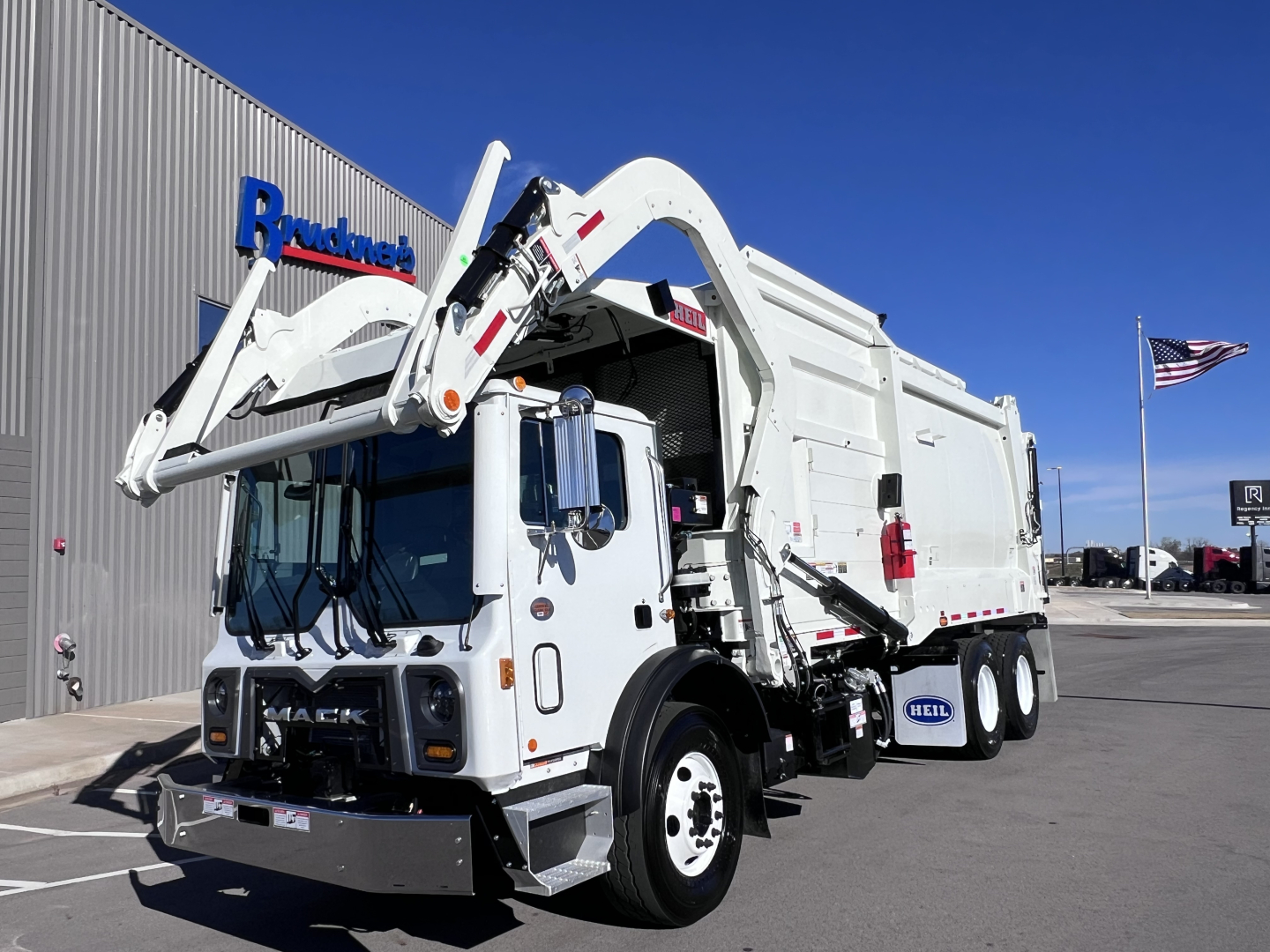 Truck mounted WAutomatic arm and rear hopper truck in serviceable condition showing Mack TE64 garbage truck with hydraulic arm and crane, white exterior.