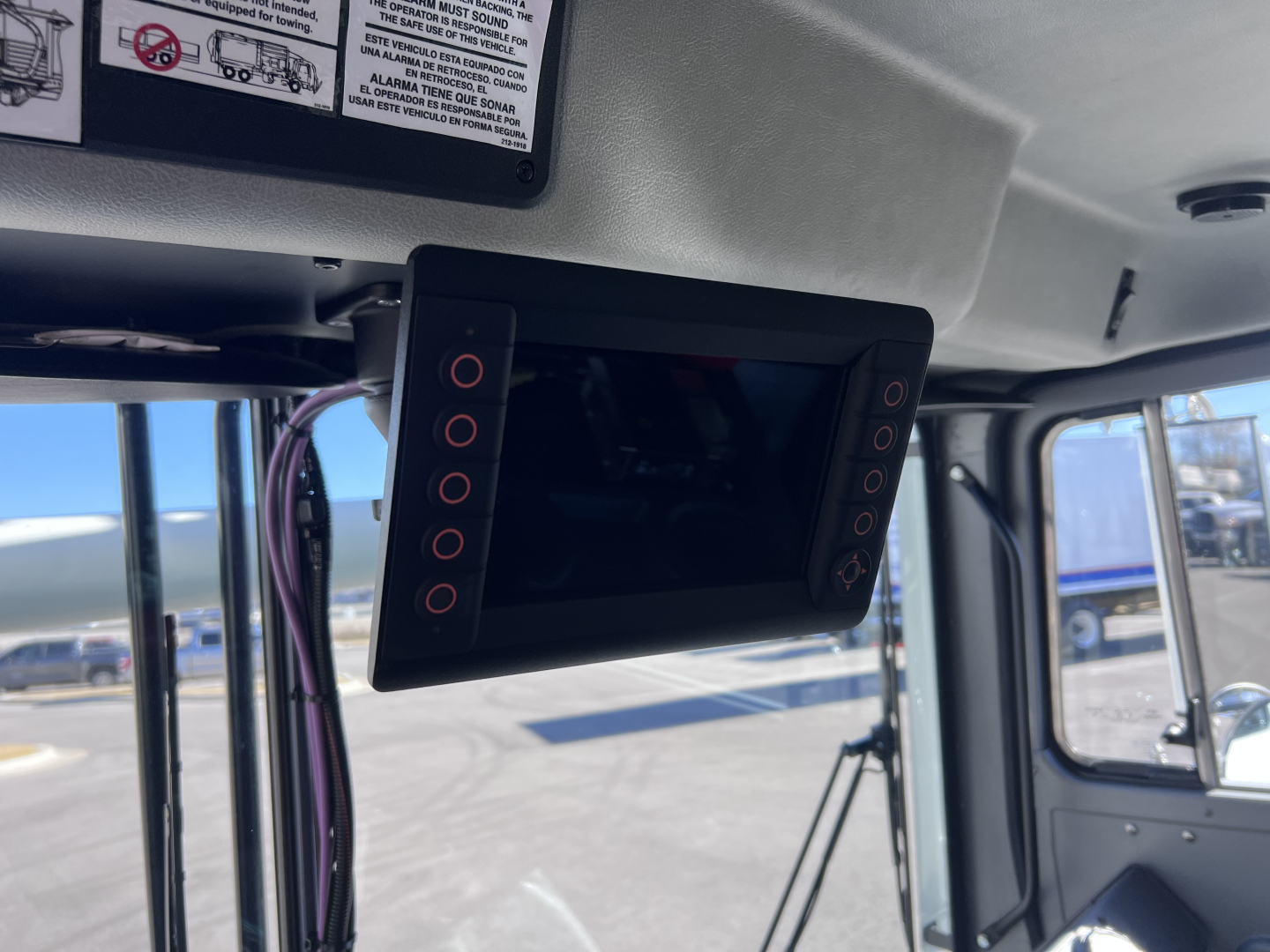 Flat-screen monitor mounted inside Mack TE64 cab with control buttons on both sides; display panel turned off.