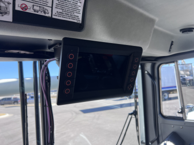Flat-screen monitor mounted inside Mack TE64 cab with control buttons on both sides; display panel turned off.