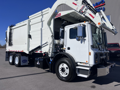 Mack TE64 truck with attached crane in front view showing white cab and garbage body.