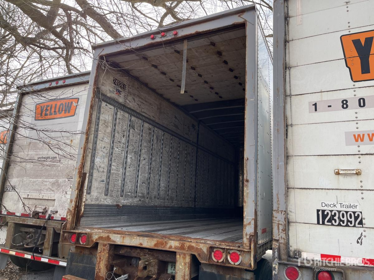 Trailer bay of a 2004 Wabash DVDBHPC trailer with open rear door, interior silver walls, and yellow label on side. VIN 1JJV281W54L887253 visible with stock 0523247.