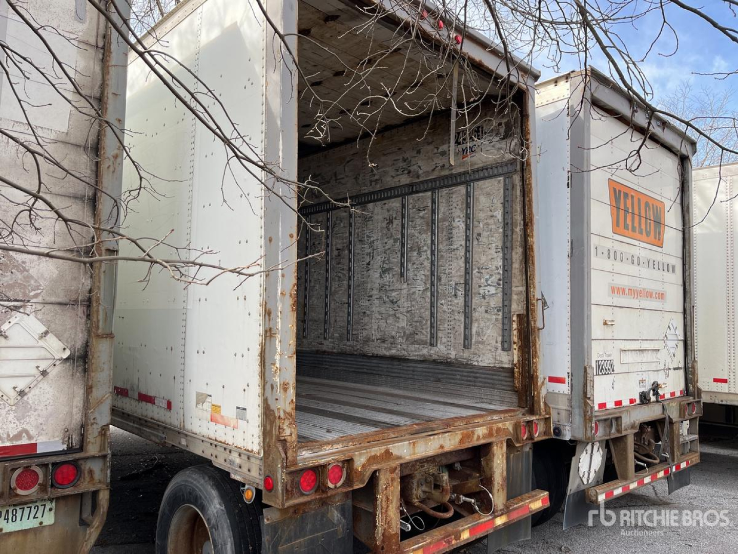 Trailer cargo area of a used 2004 Wabash DVDBHPC trailer with open rear doorway, showing metal walls, ribbed floor, and rusted frame overhanging in a yard.