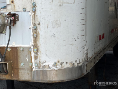 Trailer corner with metal joints and rivets showing dented grey skin and a rusted edge; rear area of a Wabash trailer with loading hardware.