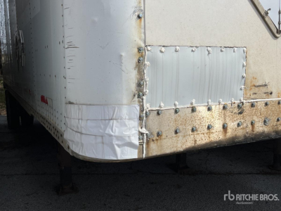 Trailer rear corner showing riveted metal panel with patch, wheel well edge, and foot support legs visible.