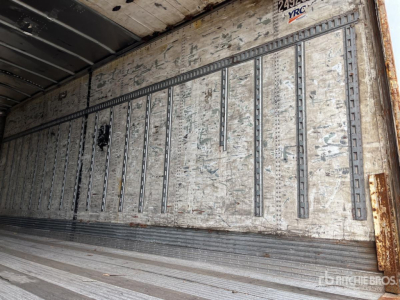 Trailer interior wall with metal rails and weathered plywood, cargo area in view; side wall channels and ribbed flooring visible.