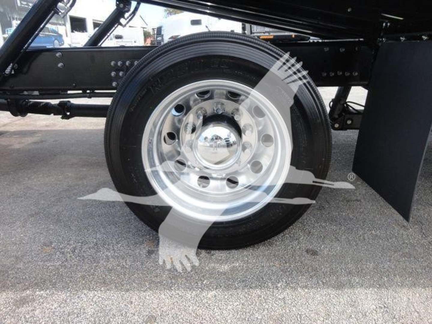 Mack MD6 truck wheel close-up showing chrome hubcap and black tire on suspension chassis.