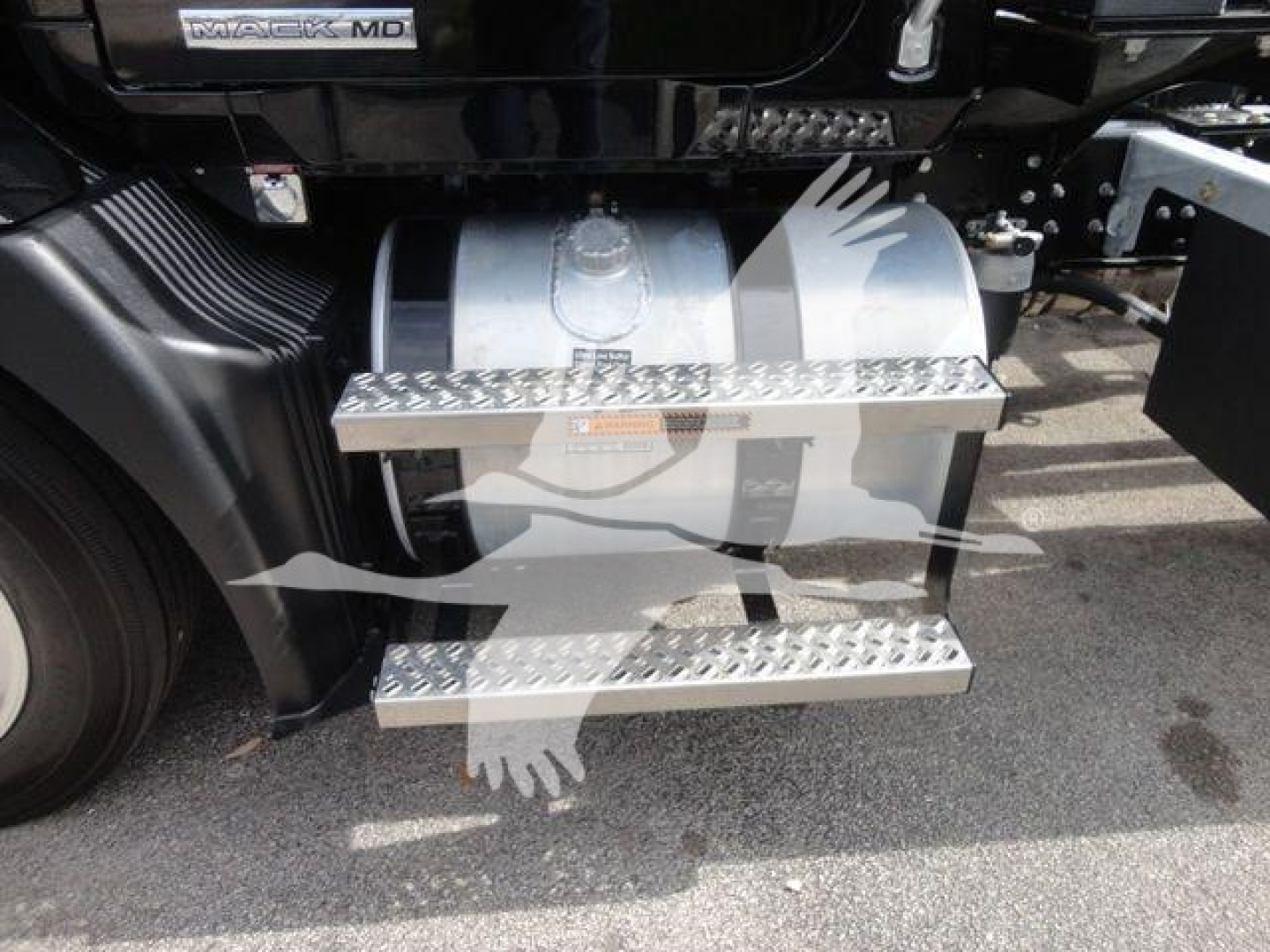 Truck side view showing metal diamond-plate steps and fuel tank along the Mack MD6 chassis. Visible text includes MACK MD6 badge on the cab.