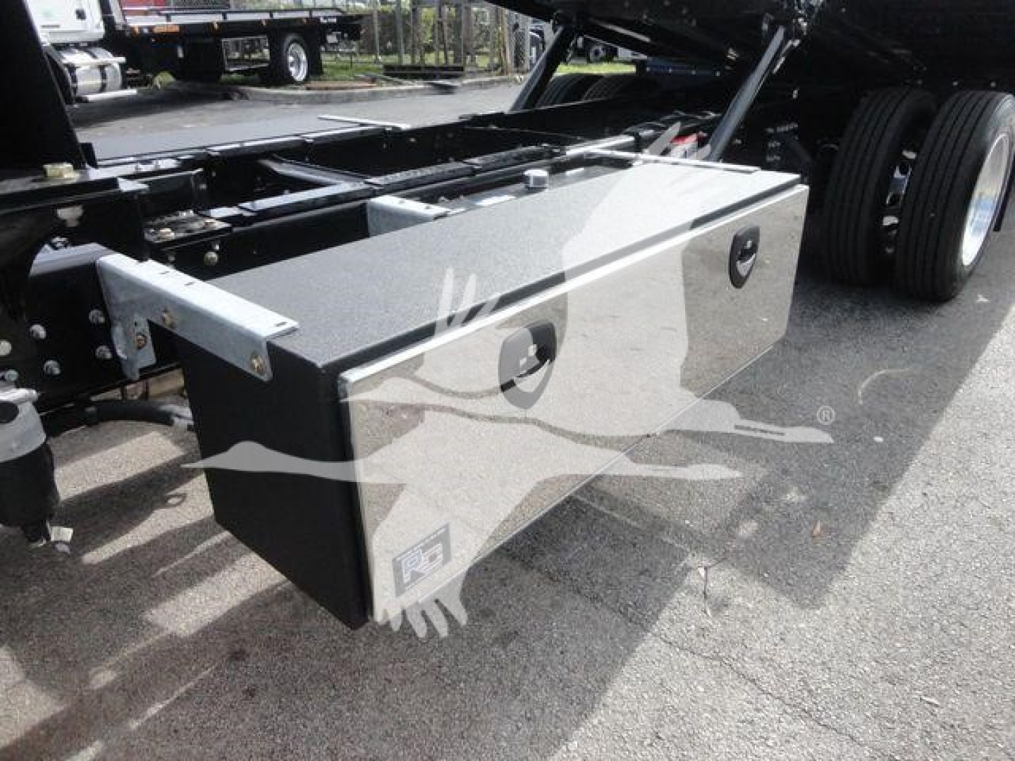 Diamond-plate toolbox mounted under Mack MD6 chassis with storage box and latching handles visible.