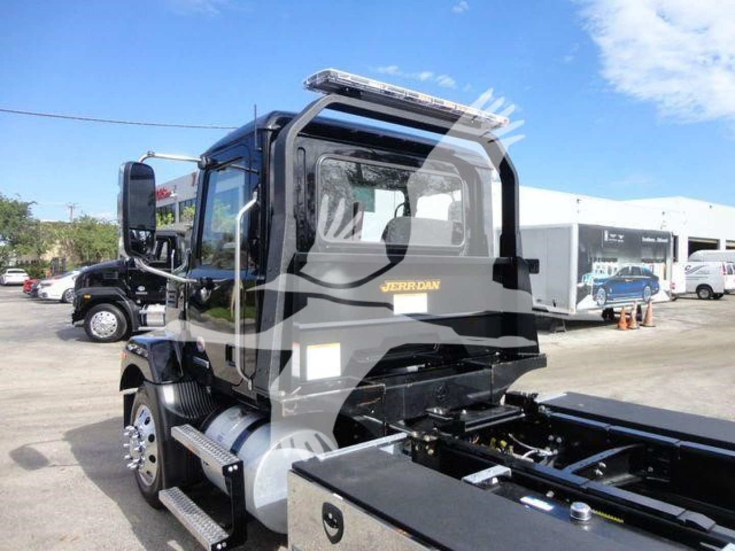 MD6 Mack truck cab and rollback bed showing Mack logo on door and fuel tanks, side steps, and equipment mounting.