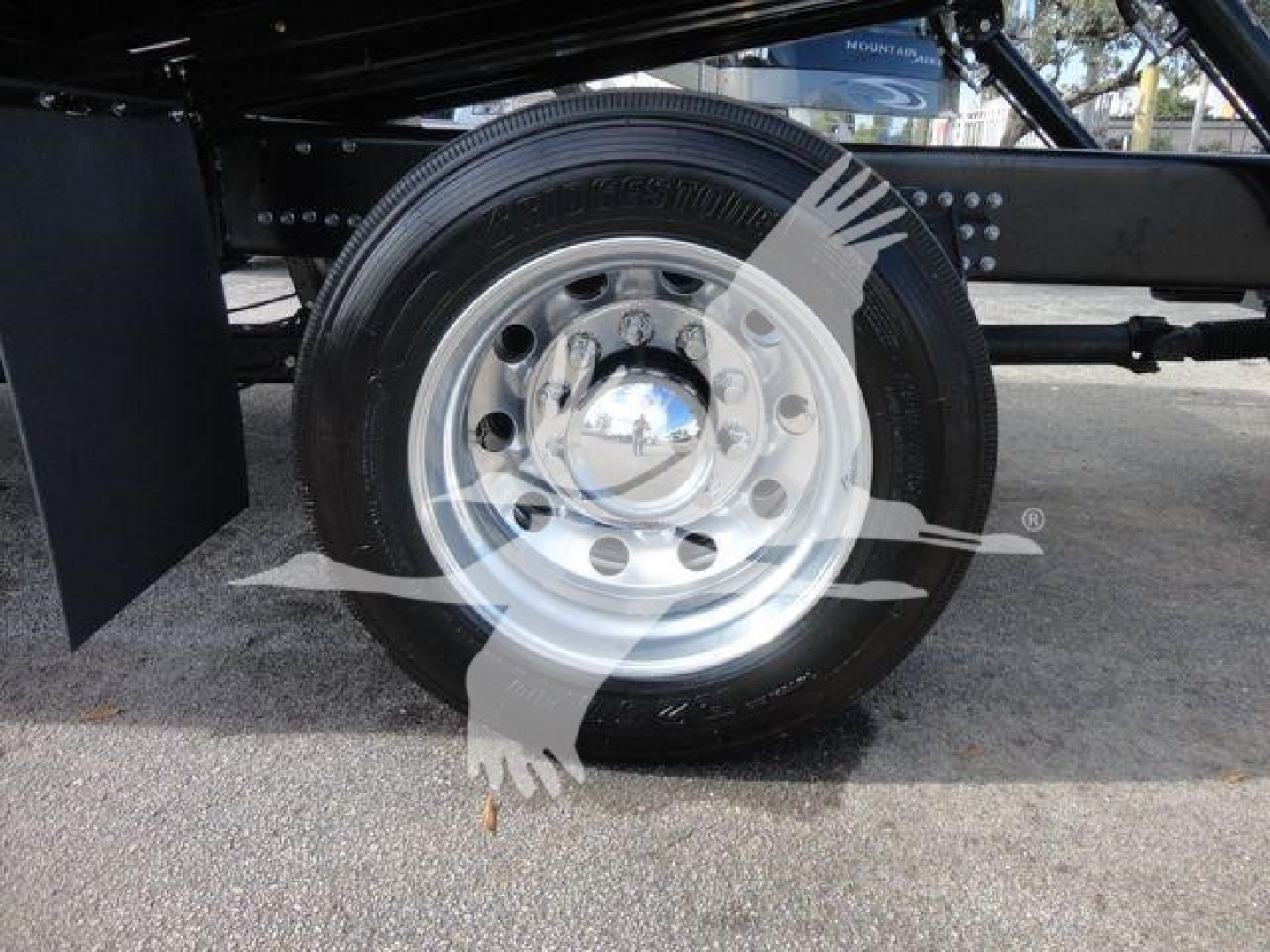 Mack MD6 truck wheel and suspension close-up showing polished steel hubcap and tire under frame rail.