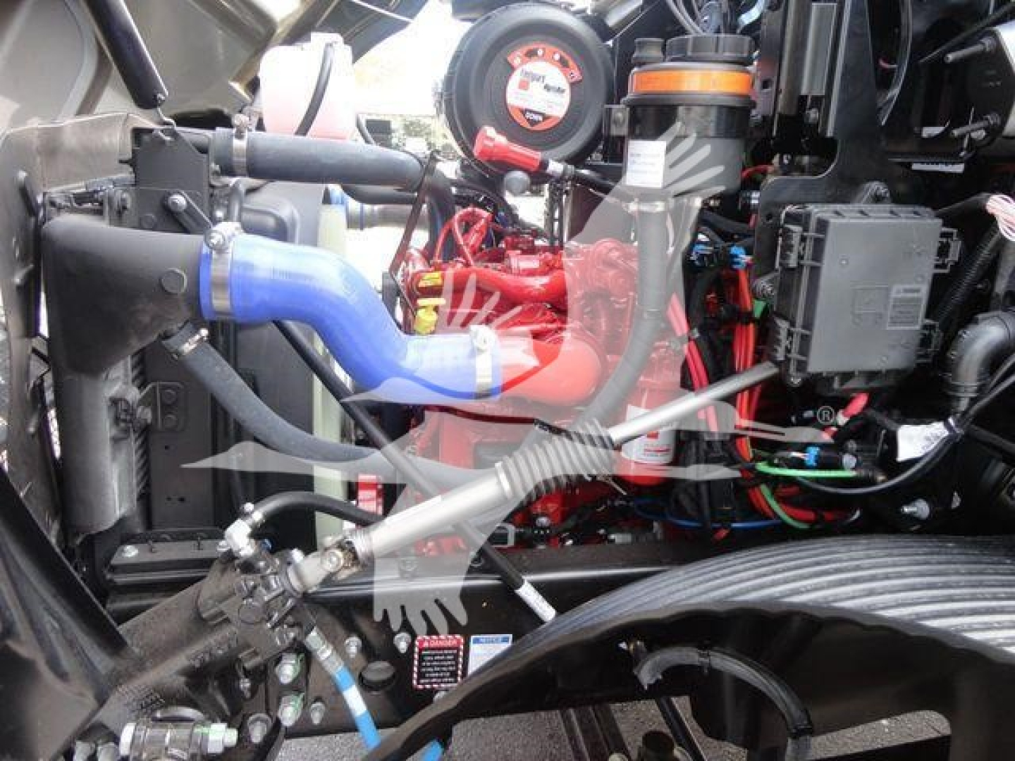 MD6 engine bay showing coolant hoses, red engine, and various hydraulic lines in a truck engine compartment.