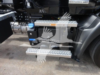 Mack MD6 truck side with aluminum diamond-plate steps and blue fill cap, showing chassis area and drivetrain components.