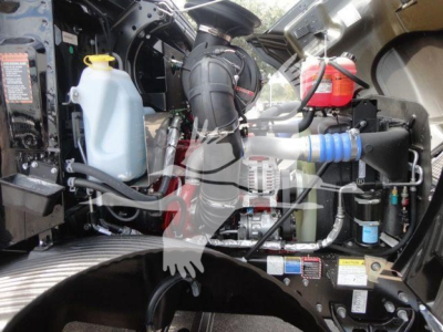 MD6 engine bay area showing coolant reservoir, hydraulic components, hoses, and wiring; label stickers and a red canister visible.