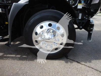 Wheel and front axle area of a Mack MD6 rollback truck showing polished aluminum rim and tire.