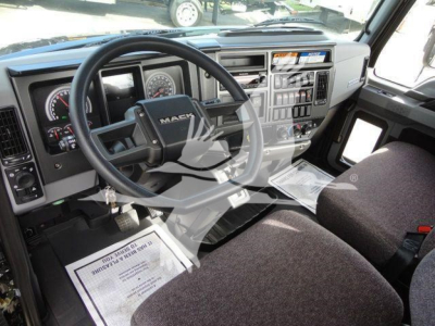 Dashboard and steering wheel of a Mack MD6 truck cab interior, showing instrument cluster, steering wheel with Mack emblem, center console, and driver and passenger seats.