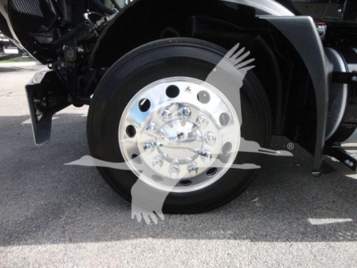 Mack MD6 truck wheel and hub with polished chrome disk showing circular lug nut pattern and tire, partial chassis nearby.