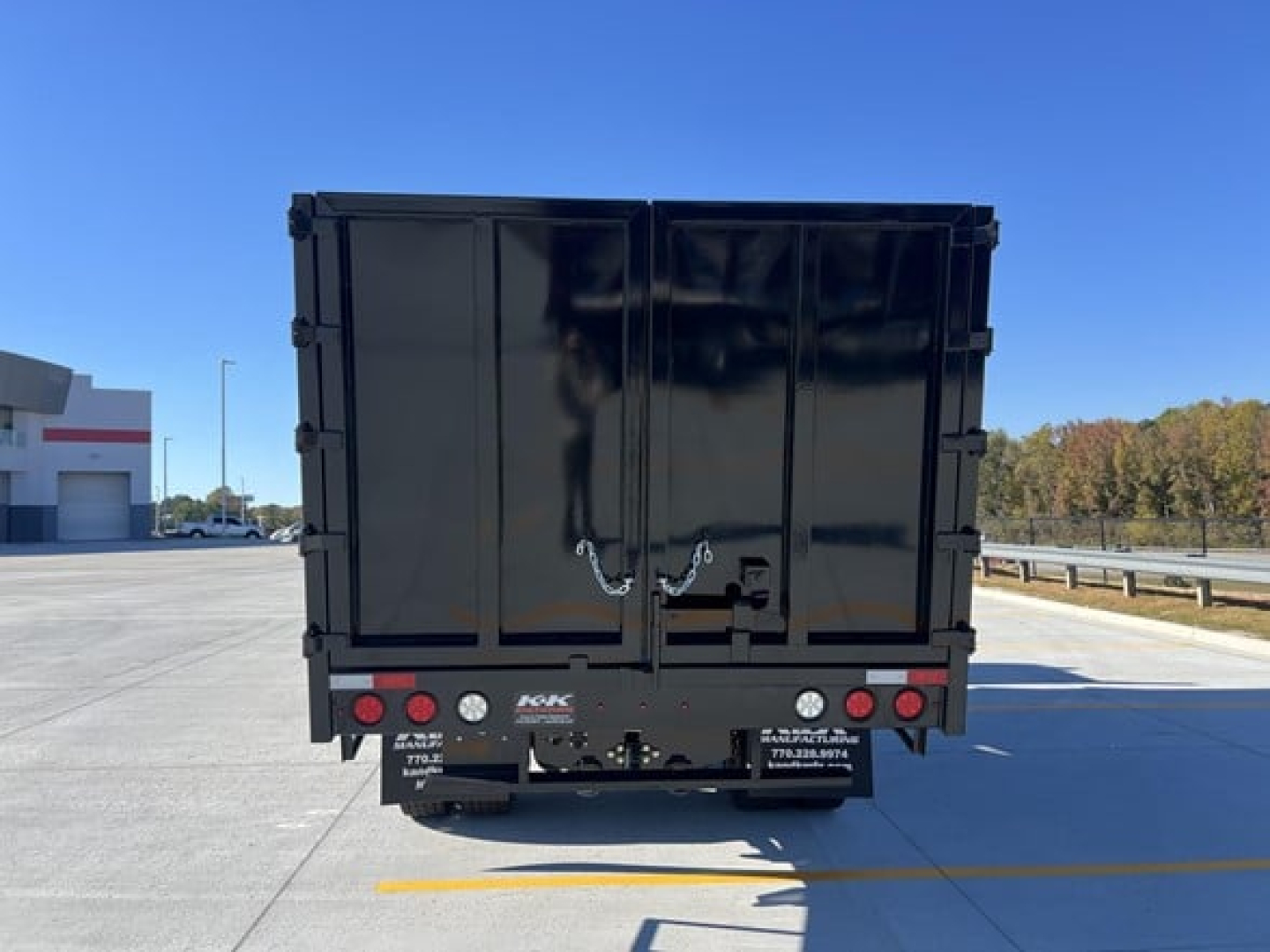 Freightliner M2 106 dump truck rear view showing black cargo bed and rear bumper with taillights and hitch.
