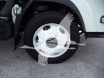 Truck wheel and fender view showing front wheel with white hubcap and partial coolant reservoir visible