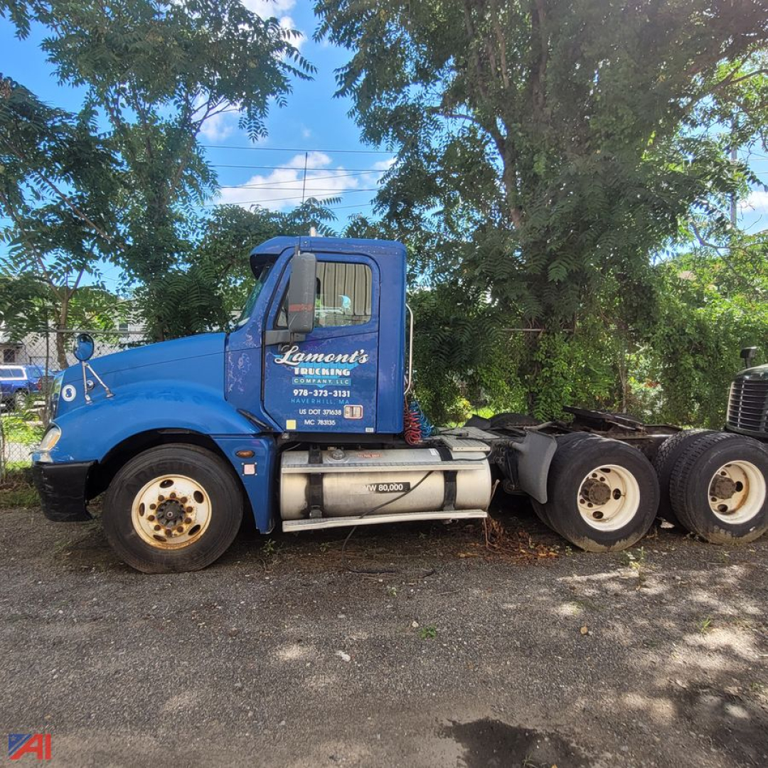 Blue Freightliner Columbia 120 conventional truck cab side view showing large fuel tanks and dual rear axles, with letters Lement's Rigging on door and contact phone on cab.
