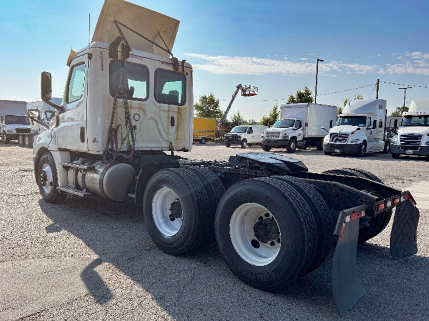 Truck cab of a 2019 Freightliner Cascadia126 tractor in a lot, chassis revealed with dual rear axles and mud flaps visible