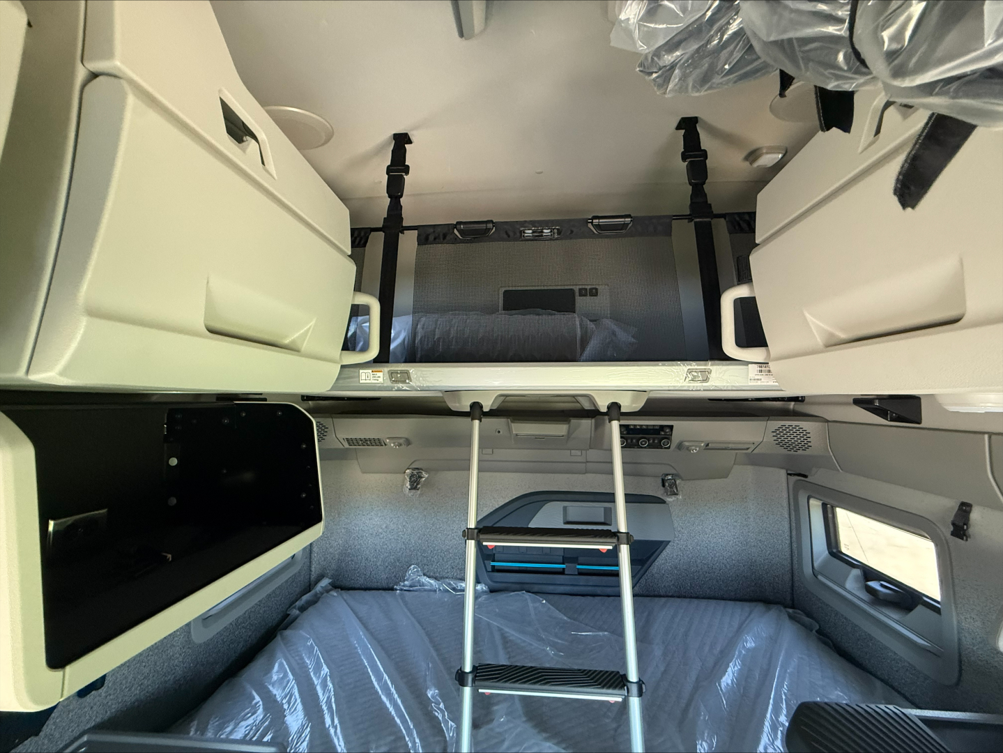Volvo VNL64T860 truck cab interior showing bunk area with ladder, storage cabinets, and overhead compartments.