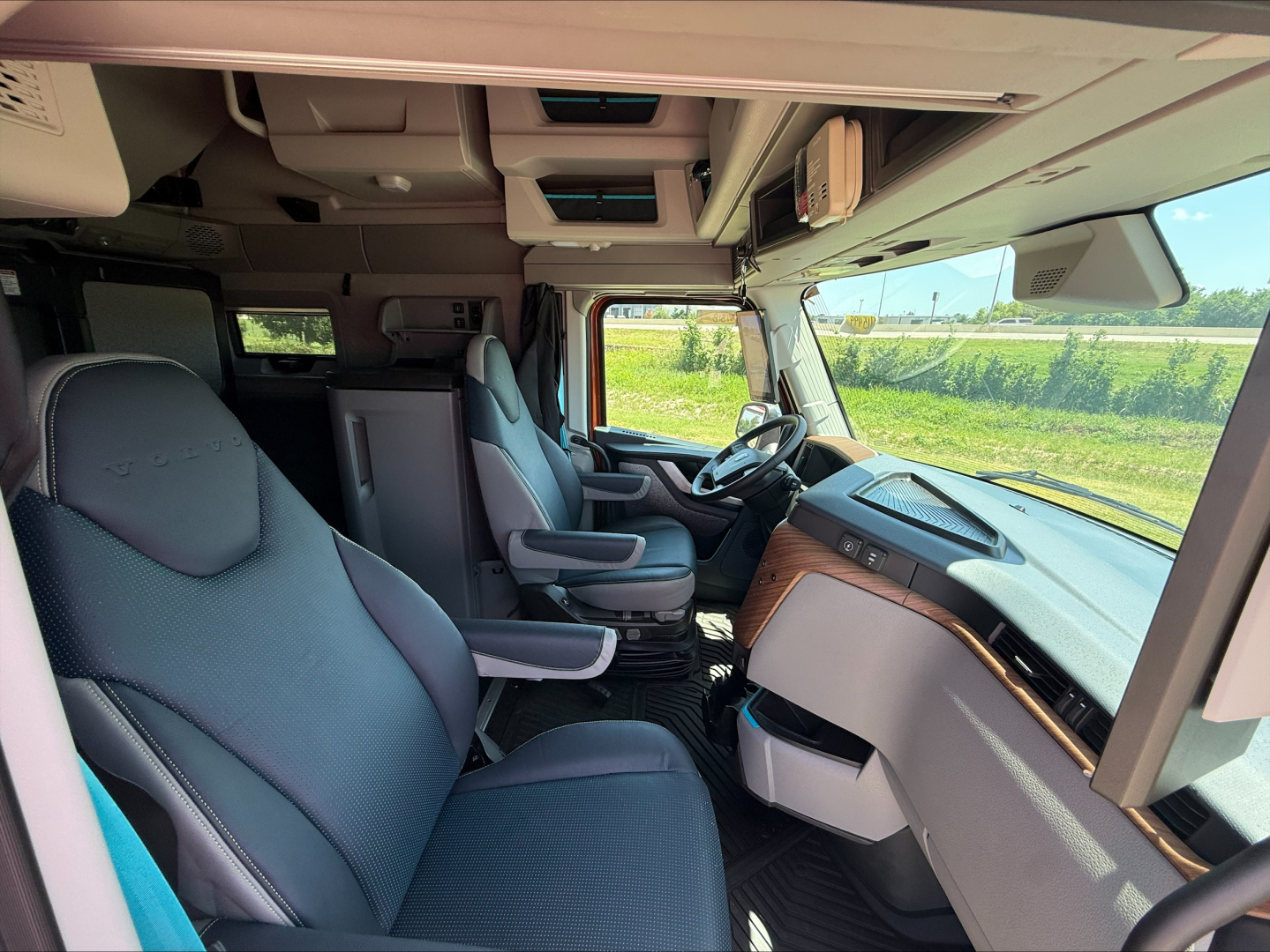 Volvo VNL64T860 interior cab view showing steering wheel, dash, and two front seats in a new truck.