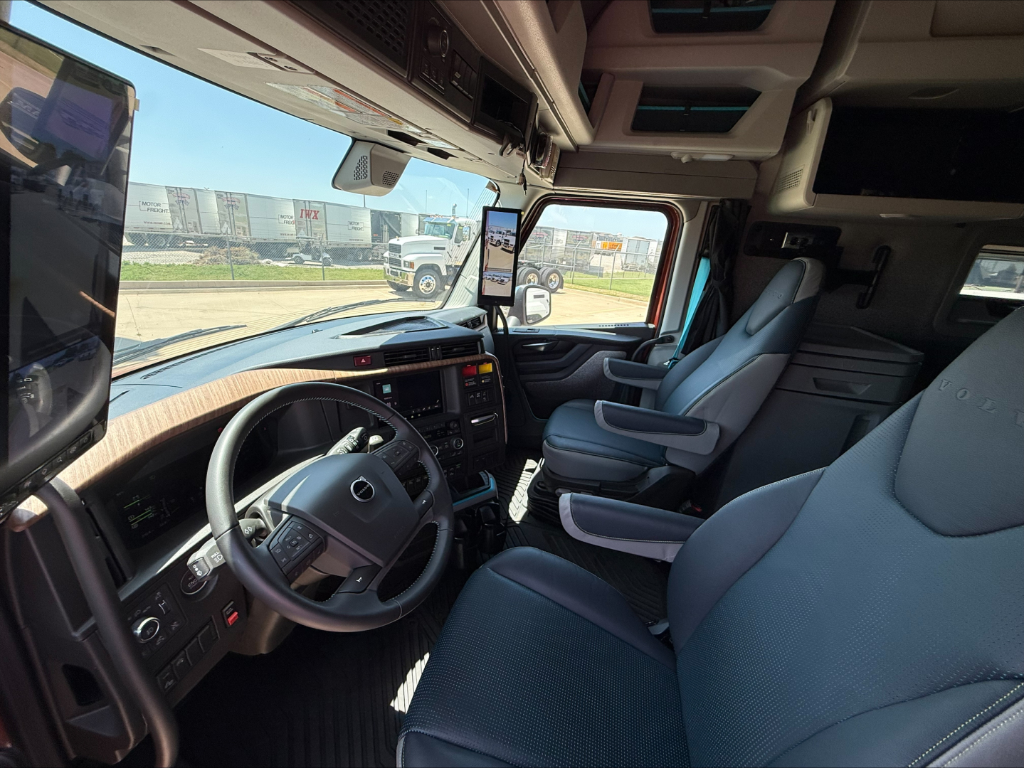 Interior of a Volvo VNL64T860 truck cab showing steering wheel, dashboard, and front seats.