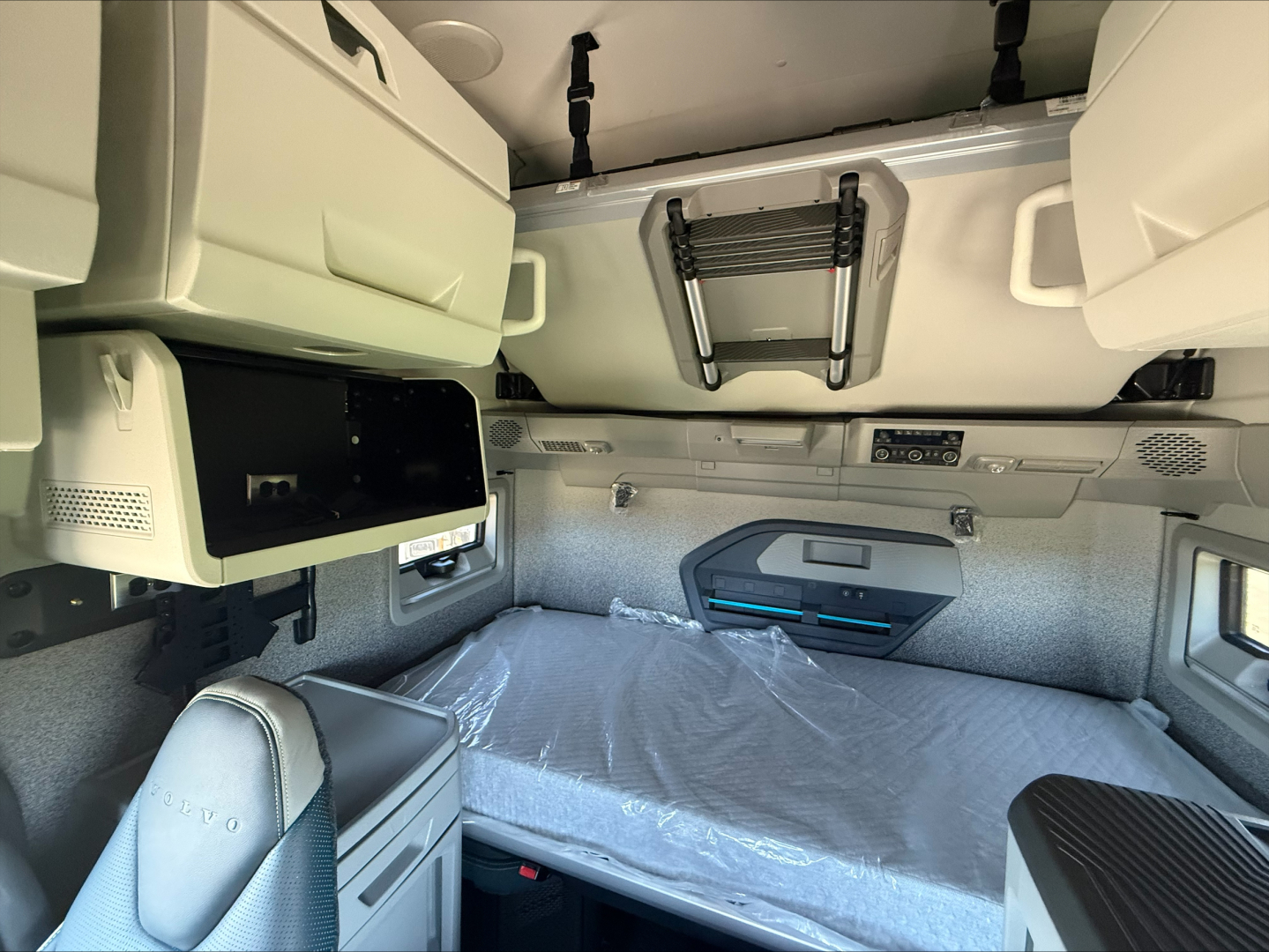 Volvo VNL64T860 sleeper cab interior showing bunk bed with overhead storage and control panel.