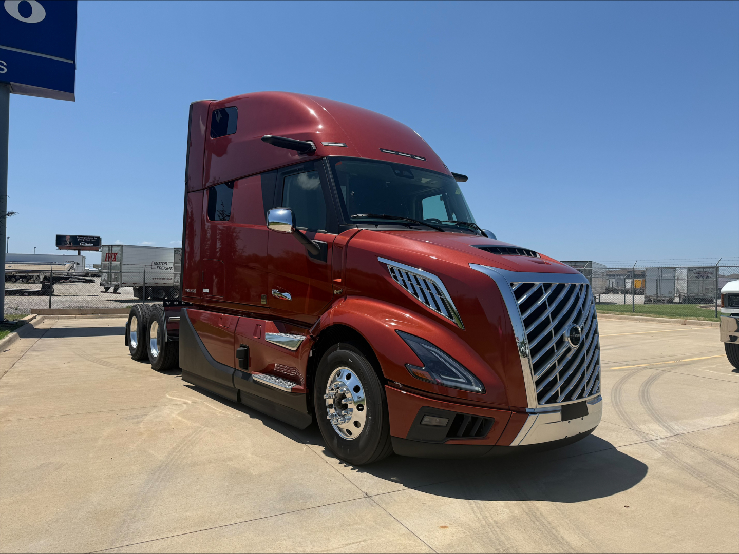 Volvo VNL64T860 tractor cab in red, front-left view showing chrome grille, dual rear wheels, aerodynamic design, daytime outdoor lot