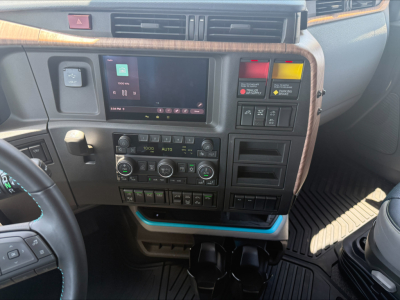 Volvo VNL64T860 dashboard view showing touchscreen infotainment, climate controls, and control switches in center console.