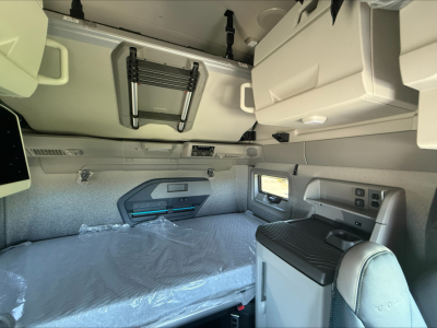 Volvo VNL64T860 sleeper cab interior showing bunk bed area and side window, overhead cabinet, and control panel.