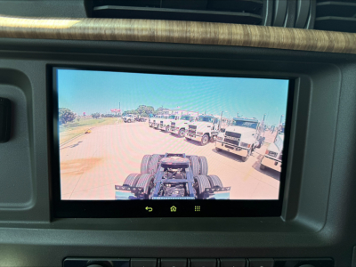 In-cabin display showing a trailer and trucks in a dealership lot; no legible text visible other than the scene.