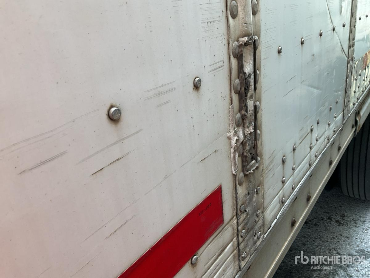 Trailer side with riveted metal panels, rear door hinge, and minor scratches; no legible brand text visible.
