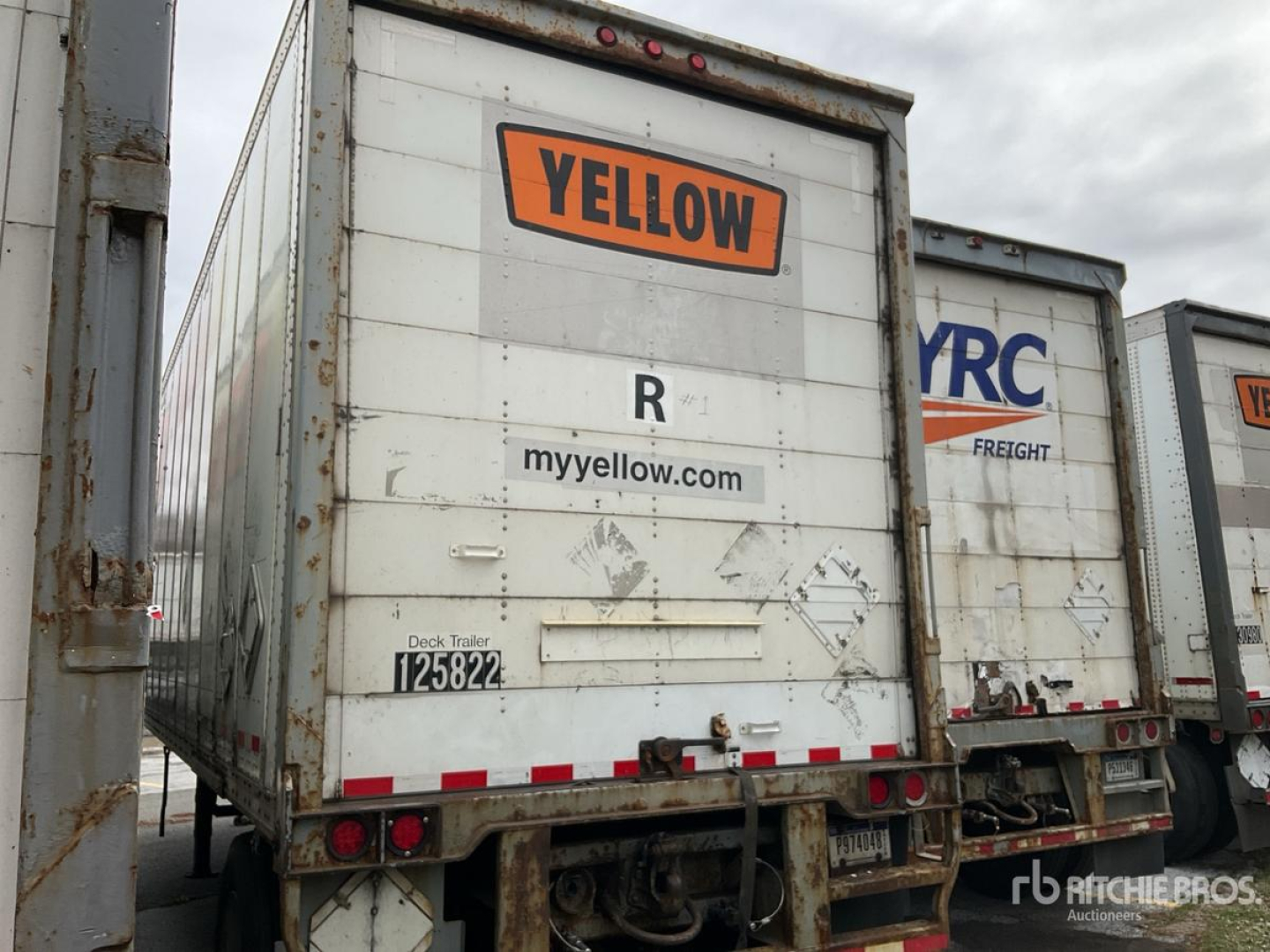 Rear view of a trailer with Yellow brand logo and R myyellow.com text visible, showing weathered surface and taillights.