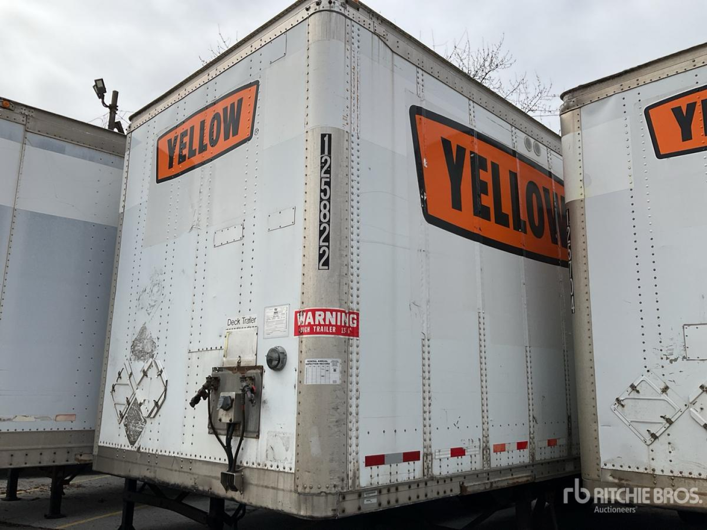 Trailer rear showing 'YELLOW' branding, silver exterior with rear door, stacked on trailer lot with other trailers nearby.