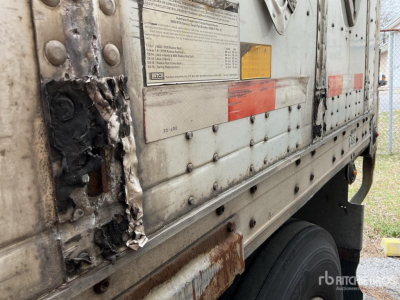 Trailer side with damaged exterior panel, dented metal, and exposed framework on a 2004 Wabash DVDBHPC trailer showing riveted panels and warning labels.