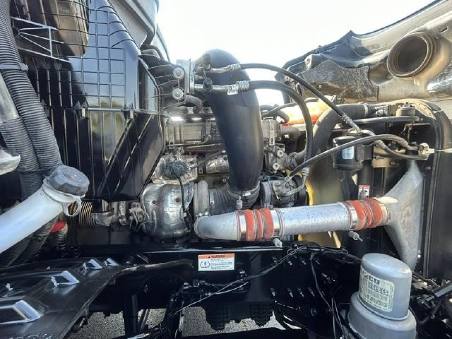 Cascadia engine bay showing intercooler piping, turbocharger, coolant reservoir cap, and various hoses; label stickers visible on components.