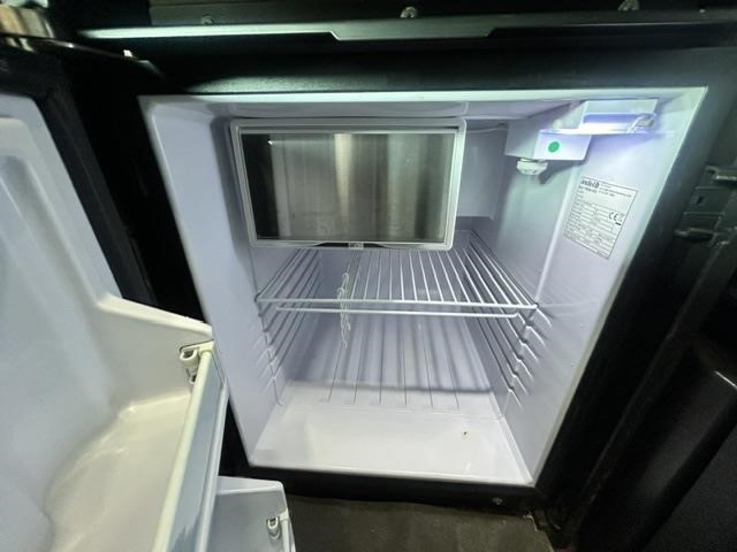 Freightliner Cascadia 126 sleeper cab interior showing empty refrigerator/freezer and upper panels.