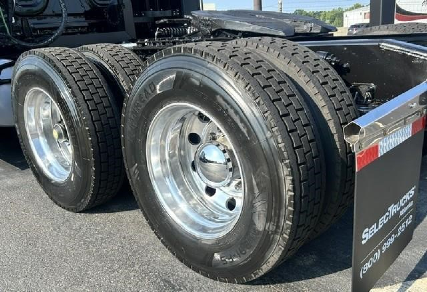 Freightliner Cascadia 126 rear dual axle wheels and mud flaps showing heavy duty tires and chrome rims.