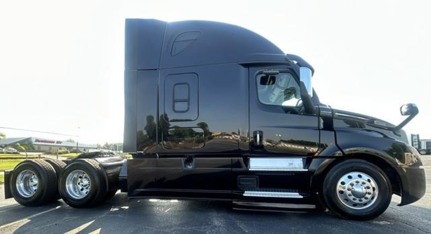 Freightliner Cascadia 126 tractor trailer side view showing sleeper cab and dual rear axles.