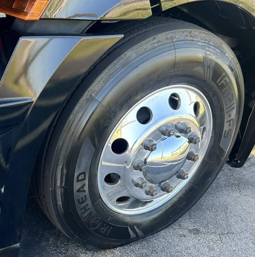 Truck wheel and front fender of a 2022 Freightliner Cascadia 126 showing polished steel hub, tire with Michelin X, and front wheel well.