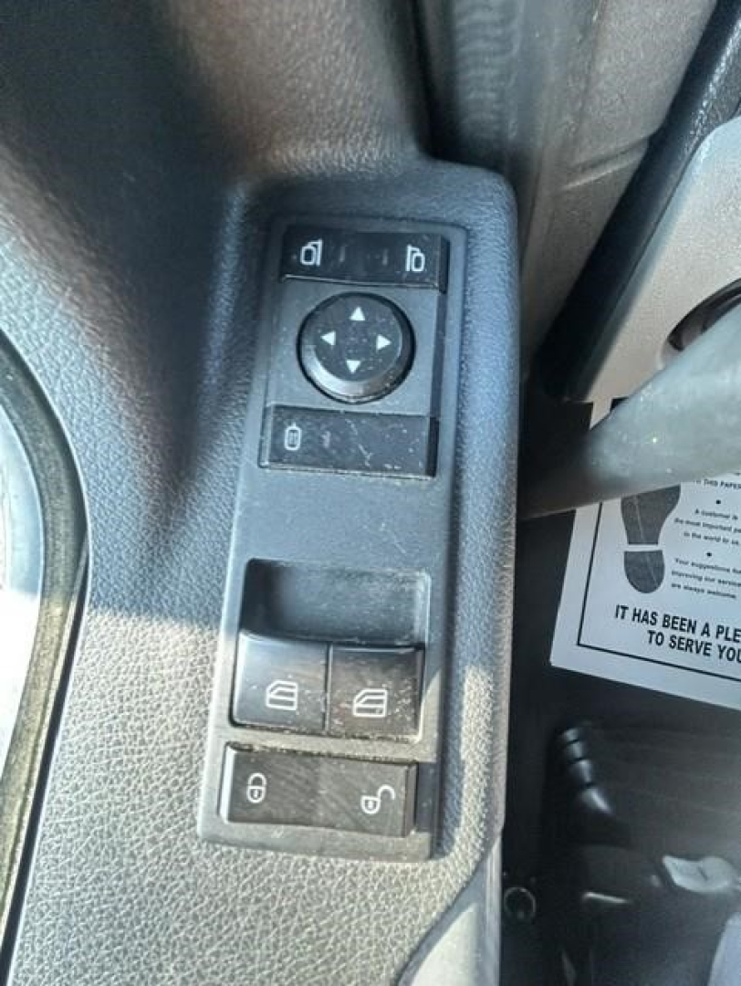 Control panel on Freightliner Cascadia door with window/mirror adjustment pad and lock switches visible.