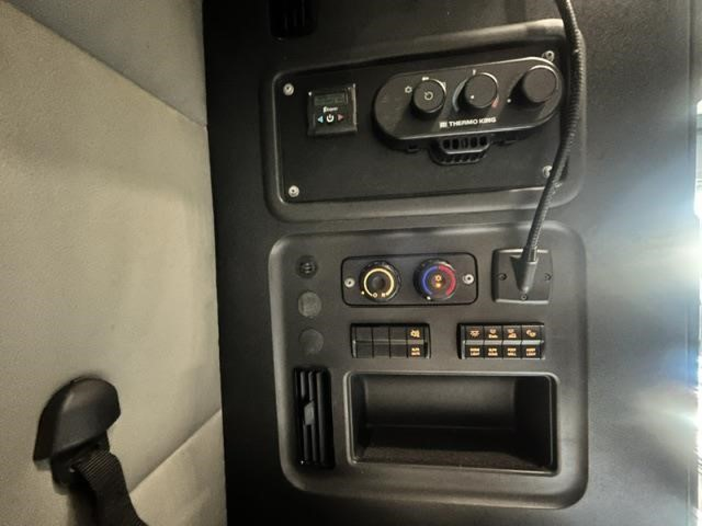 Freightliner Cascadia dash area with controls and knobs, including circular temperature/air controls and a small display, plus steering wheel edge seen.