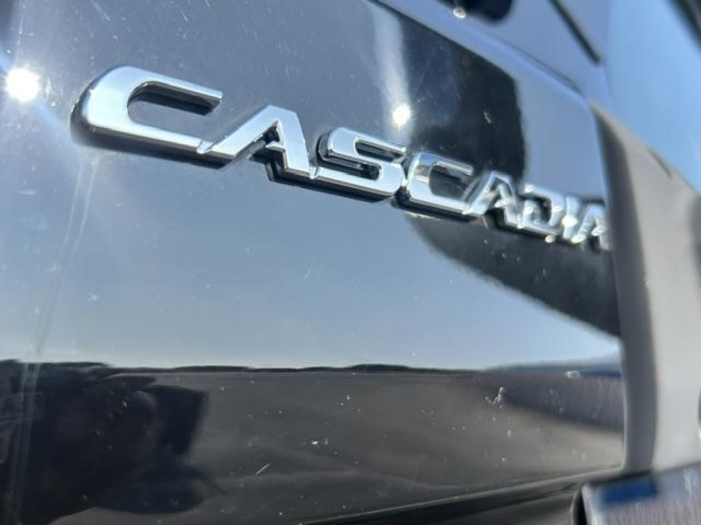 Freightliner Cascadia badge on exterior, close-up view showing 'CASCADIA' lettering on dark blue/black surface.