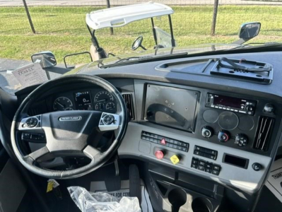 Freightliner Cascadia 126 cab interior showing steering wheel, dashboard with gauges, center console, and multiple control switches.