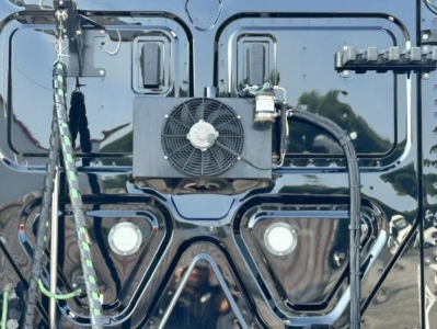 Rear view of a 2022 Freightliner Cascadia 126 sleeper cab showing an external cooling unit mounted on the back with two round lights below and a web of glossy black body panels.