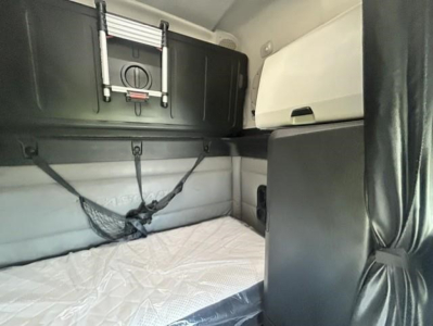 Freightliner Cascadia sleeper cab interior showing bunk area and storage compartments with mattress in place.