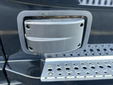 Freightliner Cascadia side access panel on fuel/def or battery area with textured step plate and surrounding black body.